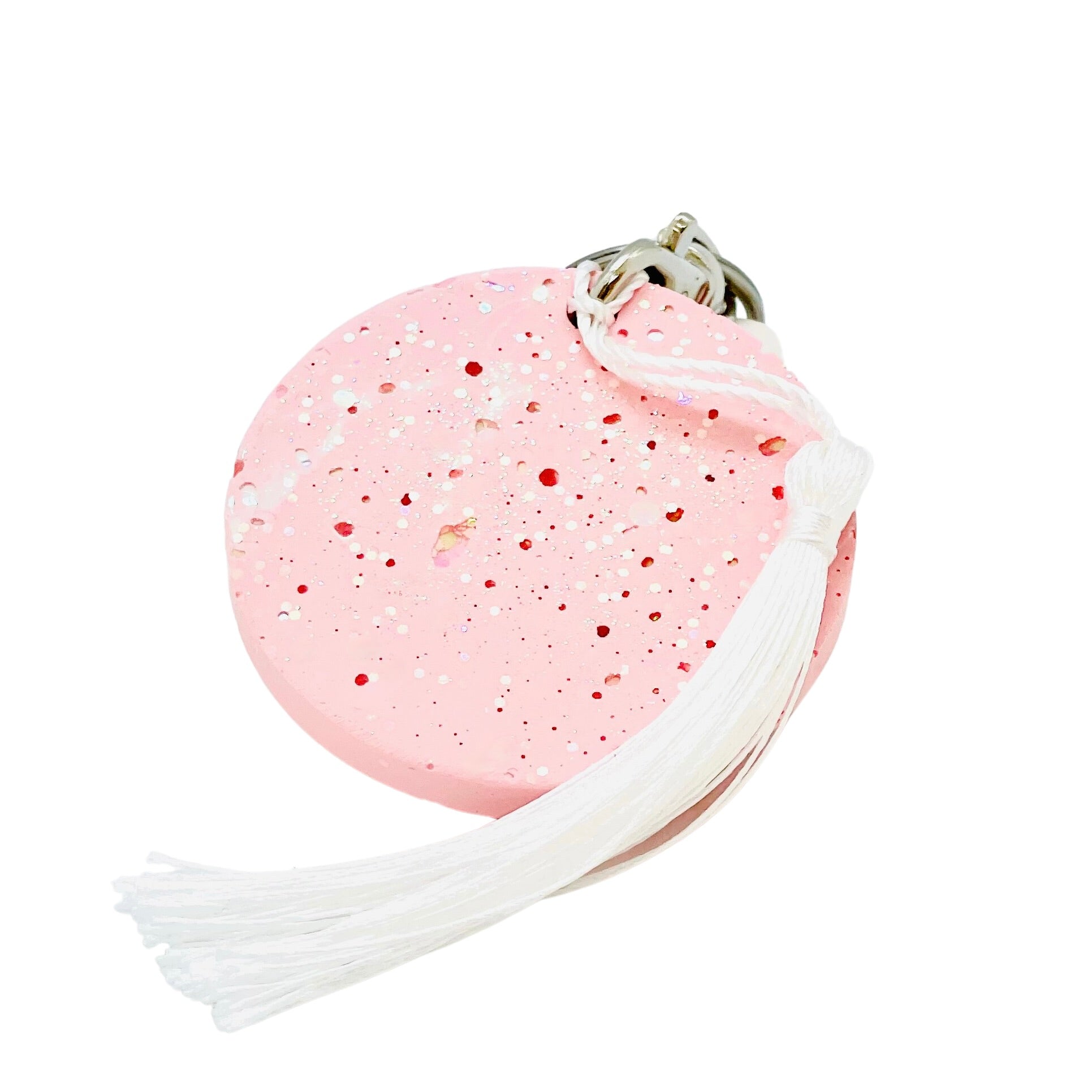 A round Jesmonite disc keyring measuring 6cm in diameter coloured with baby pink pigment and sprinkled with pink glitter.