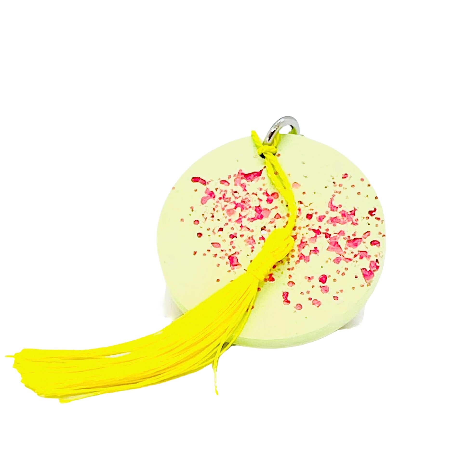 A round Jesmonite disc keyring measuring 6cm in diameter coloured with lime green pigment and sprinkled with pink glitter.