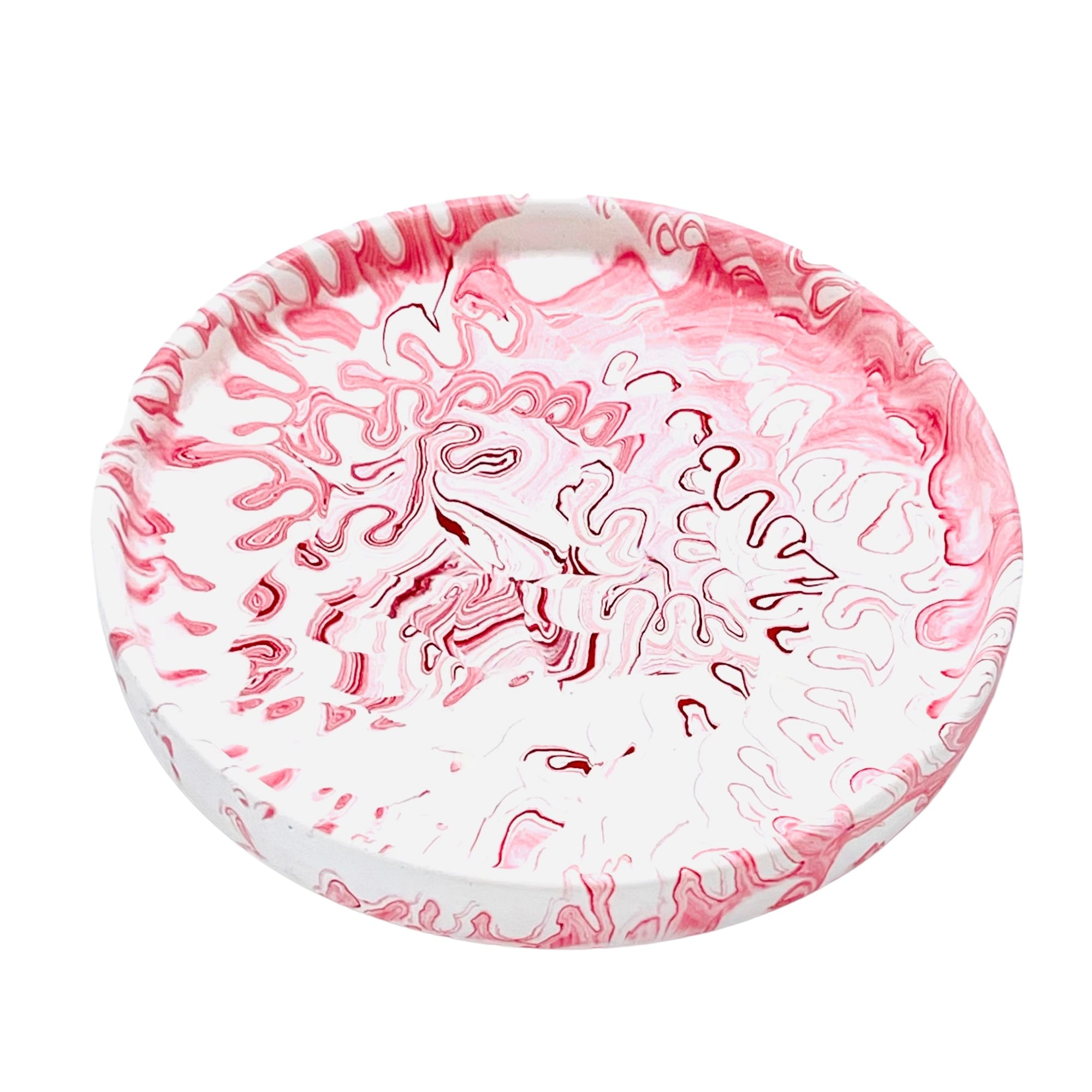A circular Jesmonite trinket tray measuring 15.4cm in diameter marbled with red pigment.