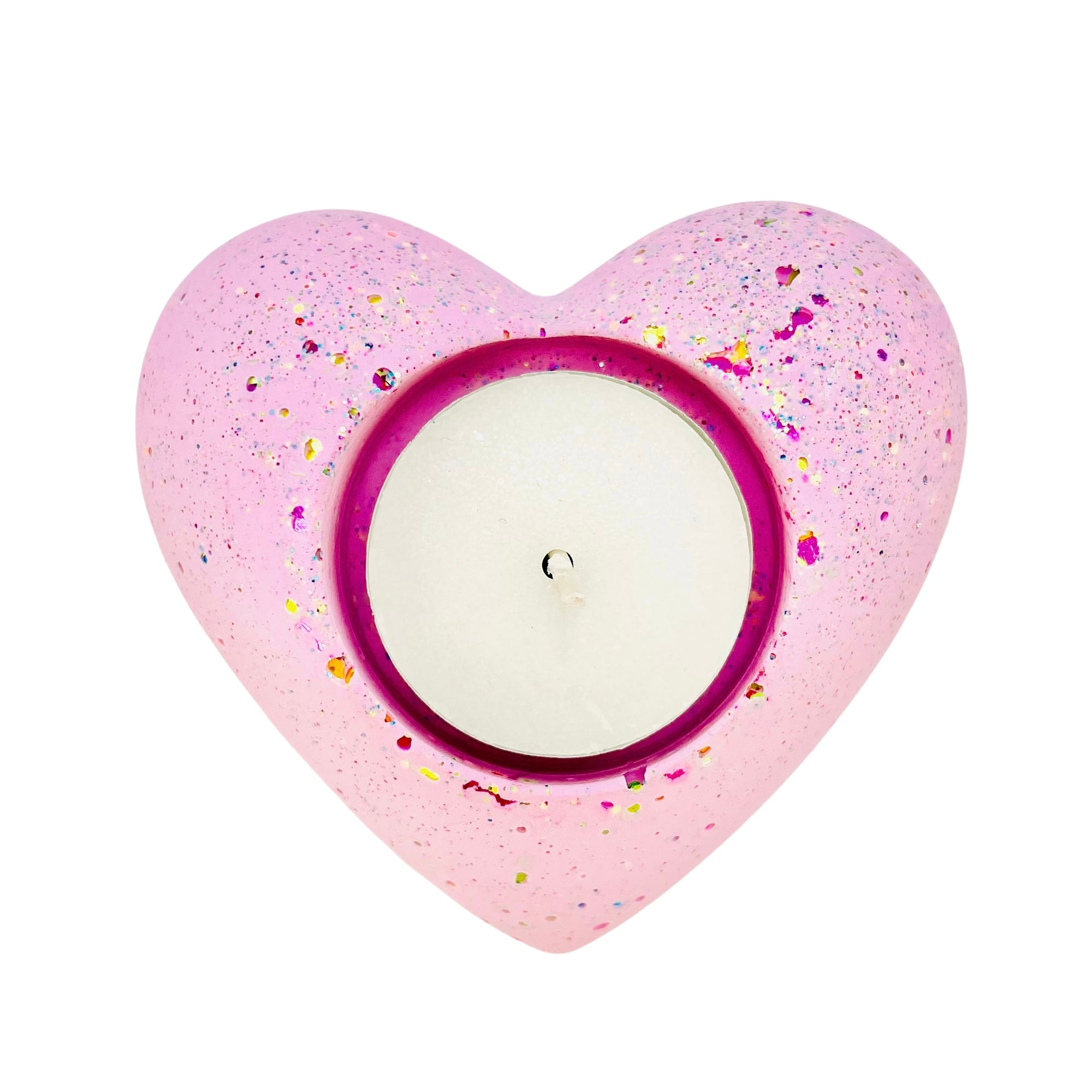 A Jesmonite heart shaped tealight holder measuring 9cm in width coloured with baby pink pigment and sprinkled with rainbow glitter. 