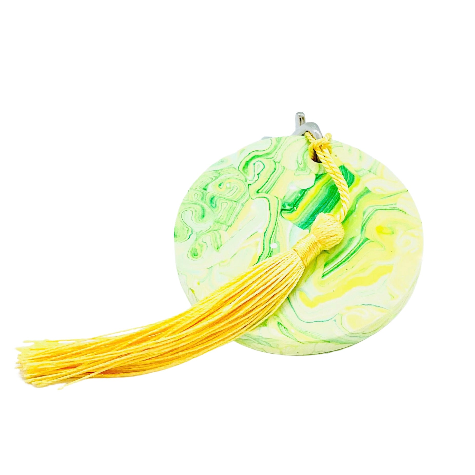 A round Jesmonite disc keyring measuring 6cm in diameter marbled with green and yellow pigment.