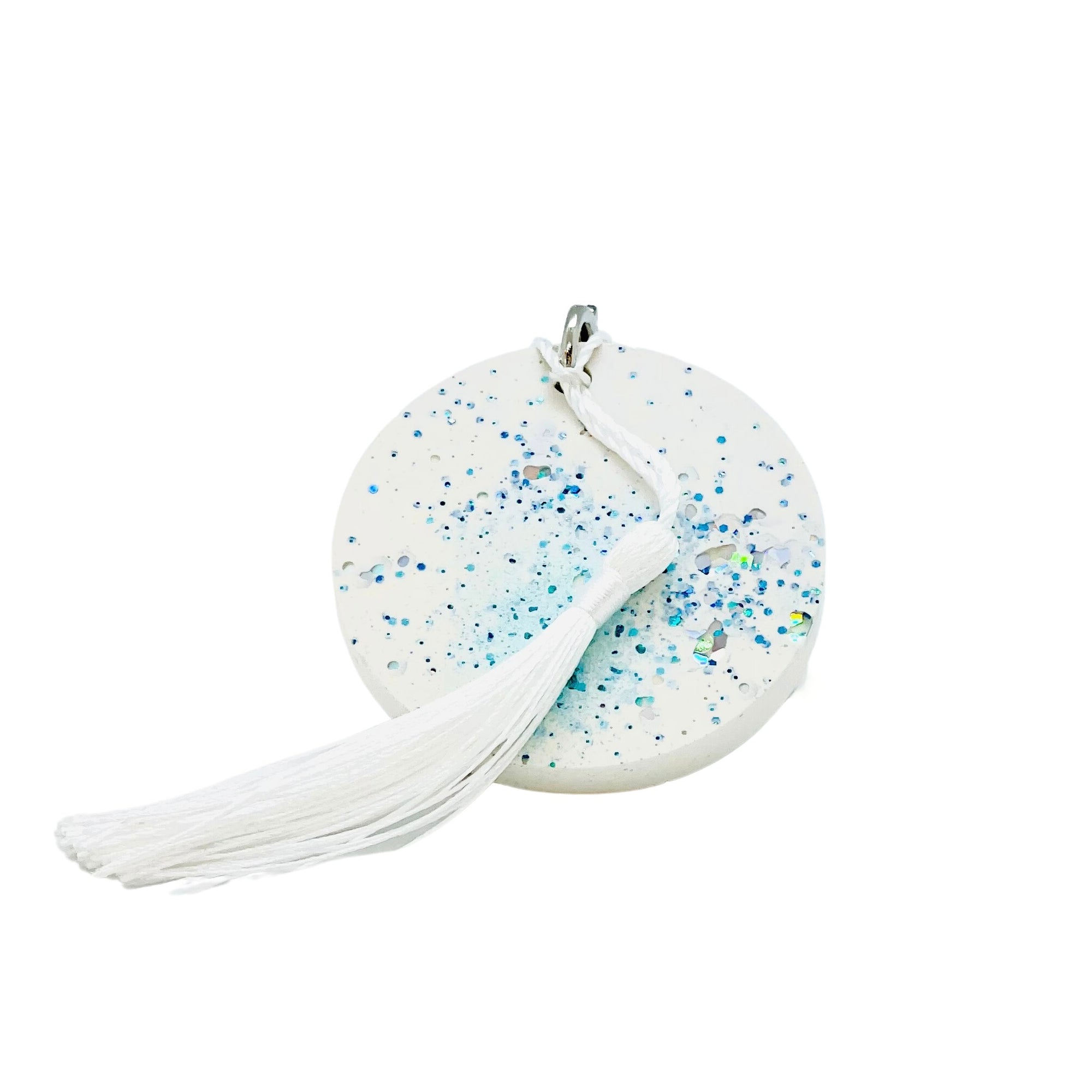 A round white Jesmonite disc keyring measuring 6cm in diameter  sprinkled with blue glitter.