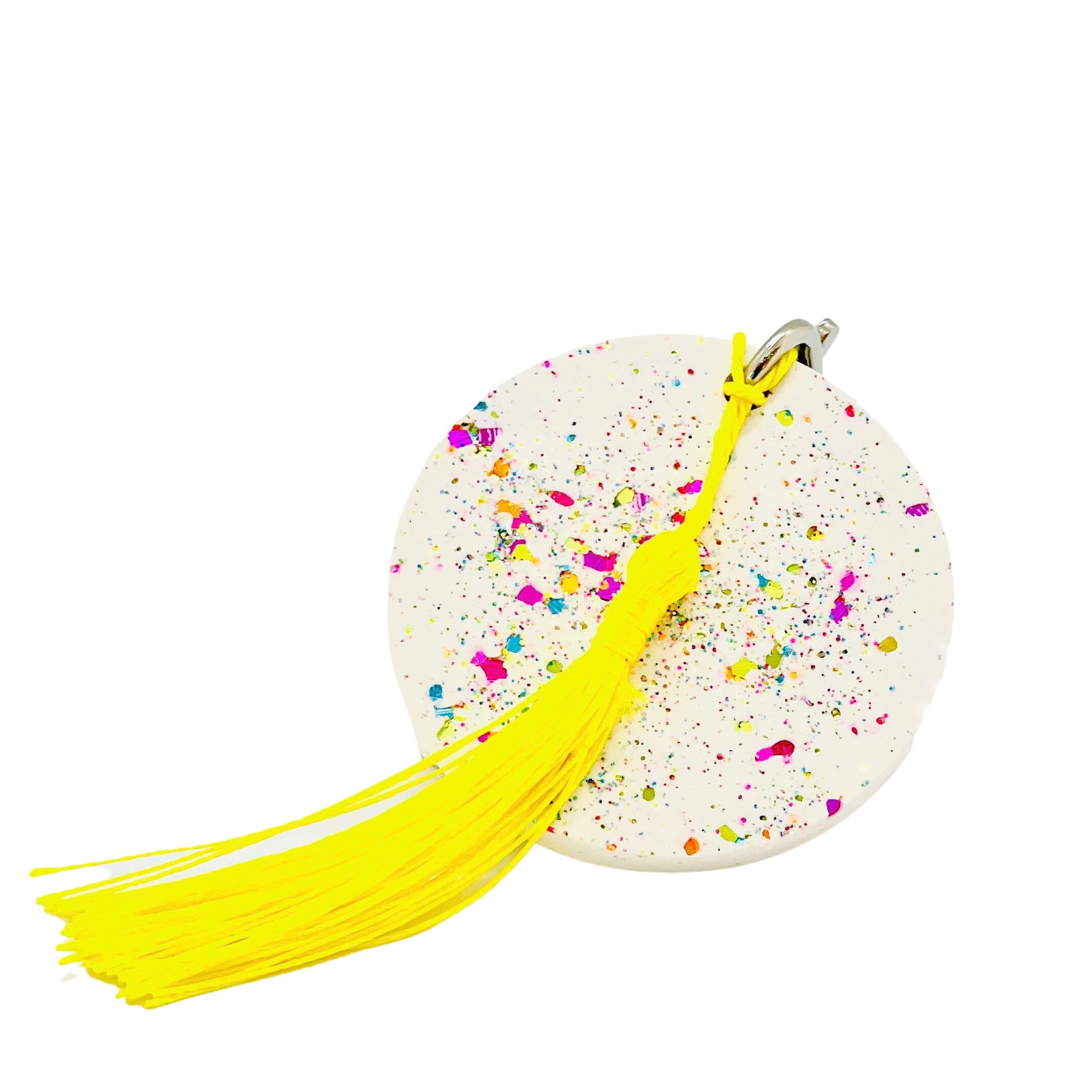 A round  white Jesmonite disc keyring measuring 6cm in diameter sprinkled with rainbow glitter.