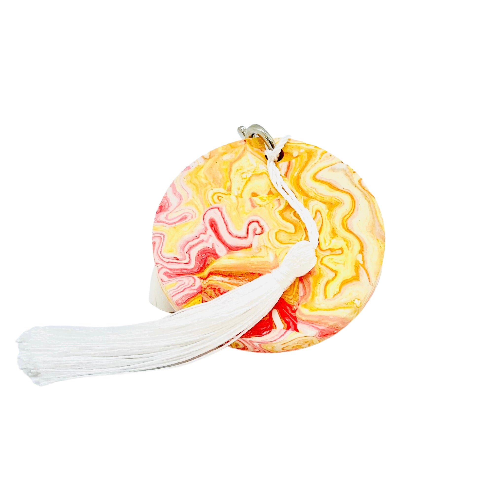 A round Jesmonite disc keyring measuring 6cm in diameter marbled with red and orange pigment.